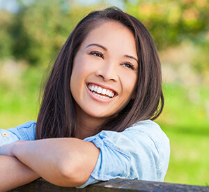 Young lady leaning on wooden rail smiling