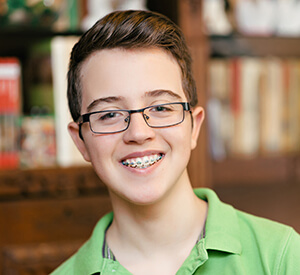 Young boy with glasses and braces smiling