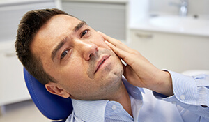 man in pain holding teeth