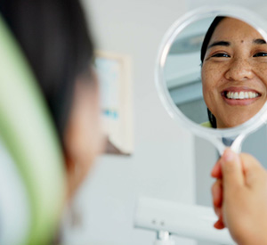 Woman smiling at reflection in dentist office