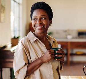 Woman smiling while enjoying cup of tea at home