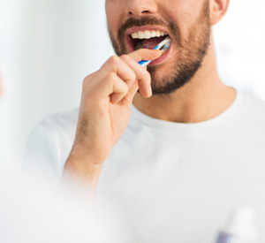 Man smiling while brushing his teeth