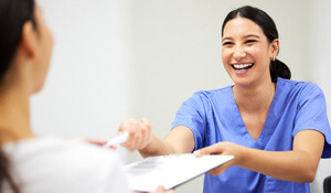 dental assistant smiling while handing patient form