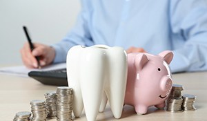 A ceramic model of a tooth, a piggy bank, and stacks of coins