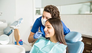 A dentist showing braces to a teenage girl