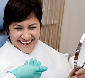 Lady holding dental mirror smiling excitedly