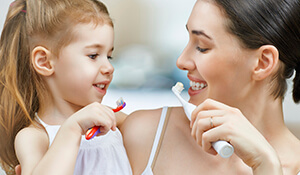 Mother and daughter happily brushing their teeth
