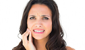 Brunette lady holding cheek in pain