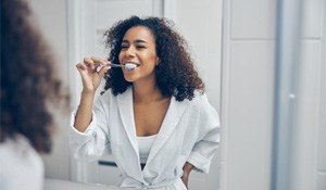 Woman in front of mirror, brushing her teeth