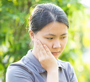 Lady holding cheek with concerned expression