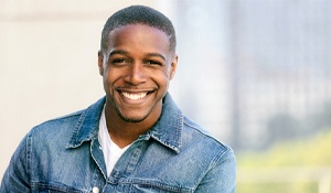 A young man wearing a denim jacket and showing off his new and improved smile