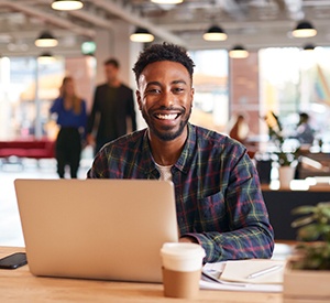 Man smiling while working on laptop in office