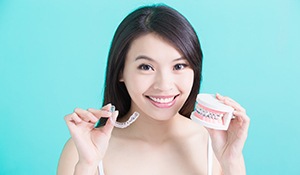 Woman holding Invisalign tray and model smile with braces