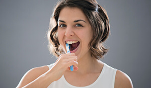 woman enthusiastically brushing teeth