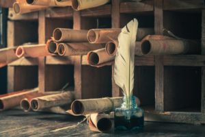 historical scrolls sitting next to an inkwell