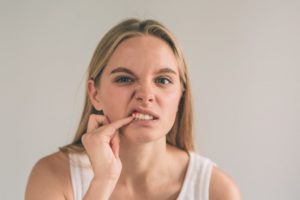 Woman poking at her painful gums should see her Richardson periodontist 