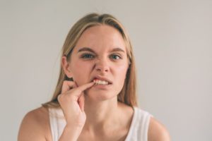 Woman poking at her painful gums should see her Richardson periodontist 