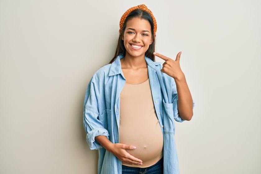 pregnant woman smiling and pointing at smile 