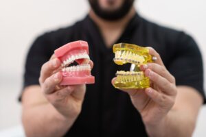 Person holding teeth models with braces and aligners